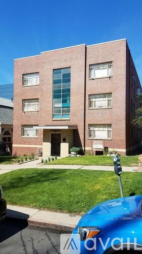 A brick building with a blue car parked in front.