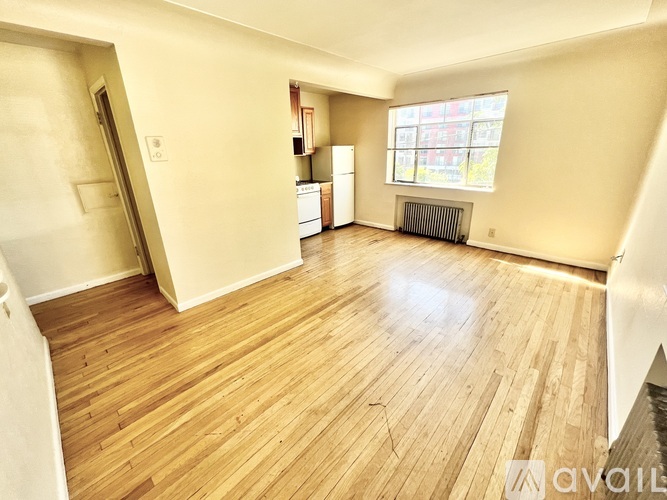 A spacious room with wooden flooring and a window.