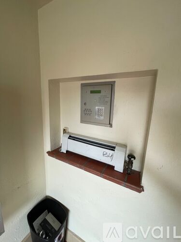 A small room with a whiteboard and a black trash bin.