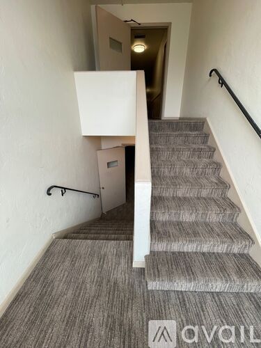 A staircase with a carpeted runner and a black handrail.