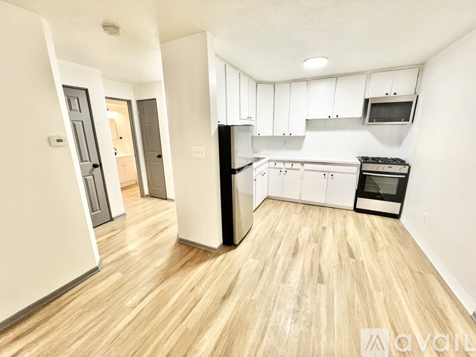 A kitchen with white cabinets and a wooden floor.