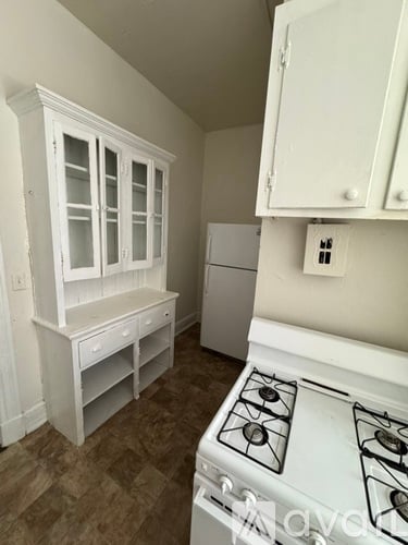 A white stove top oven sits in a kitchen with white cabinets.