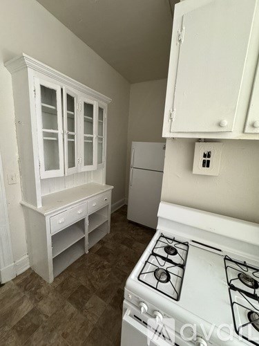 A white stove top oven sits in a kitchen with white cabinets.