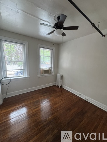 A room with a ceiling fan and two windows.