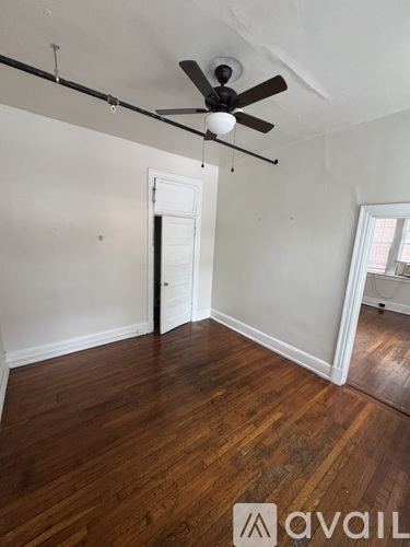 A room with a ceiling fan and wooden floors.