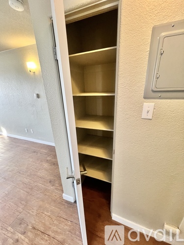 A white door is open to a room with a shelving unit.