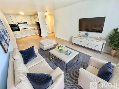 A living room with a white couch and a television on the wall.