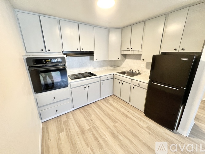 A kitchen with white cabinets and a black fridge.