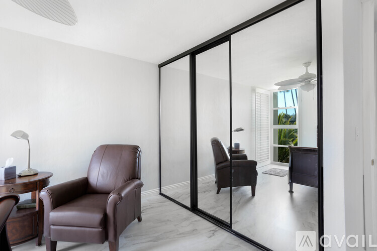 A living room with a brown leather chair and a mirrored wall.