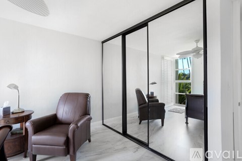 A living room with a brown leather chair and a mirrored wall.