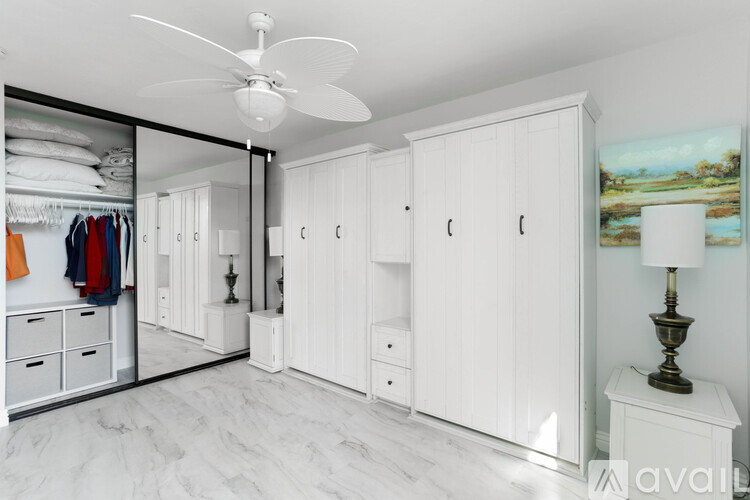 A spacious walk-in closet with white cabinetry and a marble floor.
