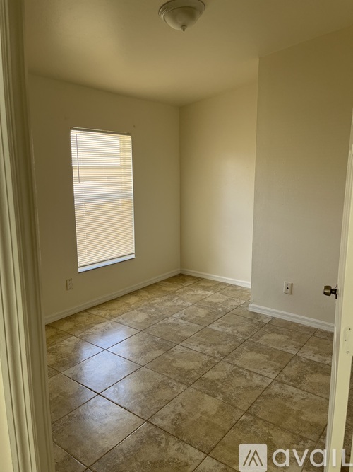 A room with a tiled floor and a window with blinds.