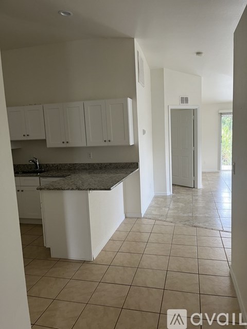 A kitchen with white cabinets and a granite countertop.