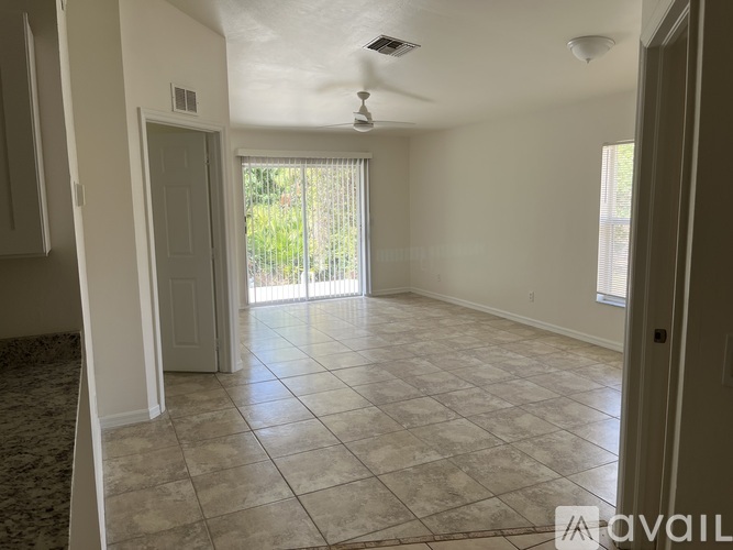 A spacious room with tiled flooring and a sliding glass door leading to a garden.