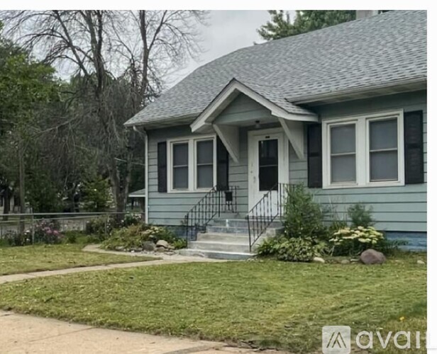 A house with a grey front yard and a black metal railing.