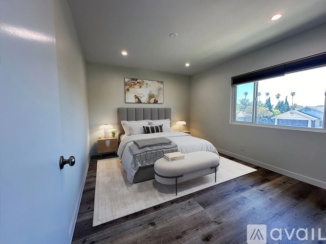 A bedroom with a large bed and a window overlooking a residential area.