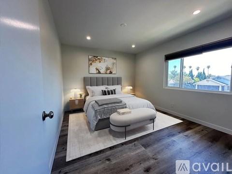 A bedroom with a large bed and a window overlooking a residential area.