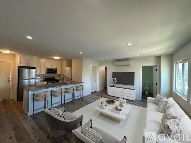 A modern living room with a kitchen area in the background.