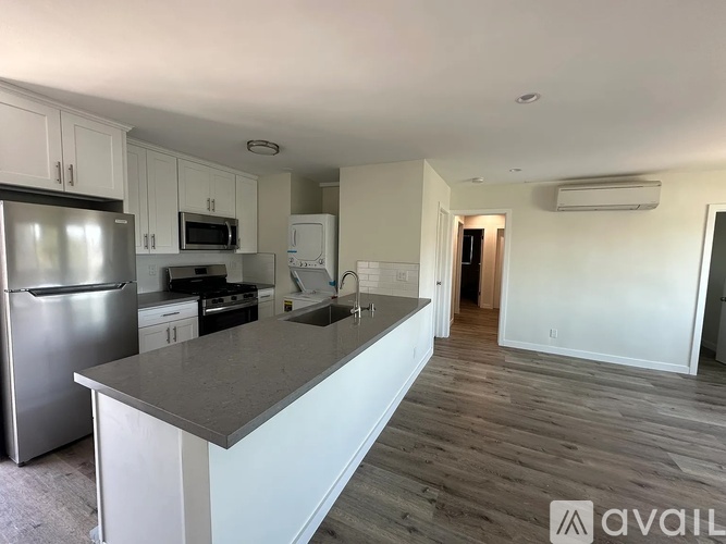 A kitchen with a refrigerator, microwave, oven, and sink.