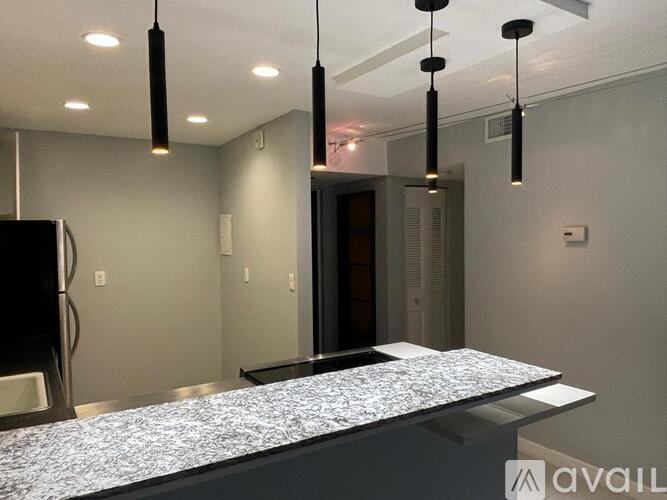 A modern kitchen with a granite countertop and pendant lights.