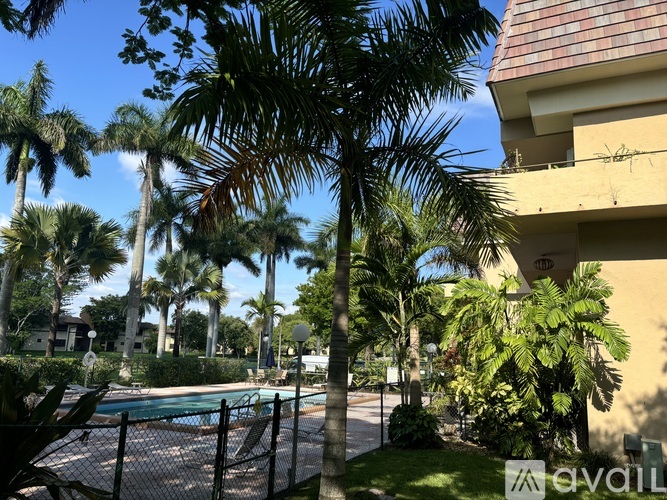 A pool surrounded by palm trees and a fence.