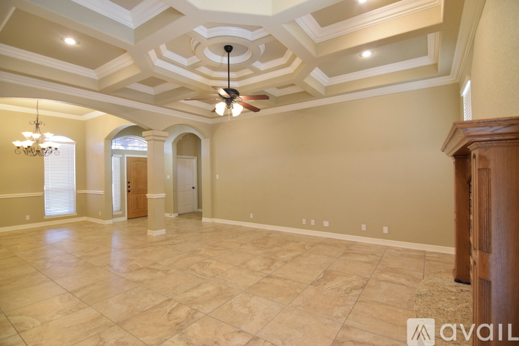 A spacious room with a fan and a chandelier.