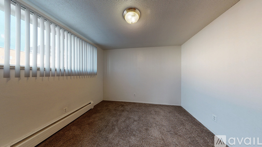 A room with a carpeted floor and a window with blinds.