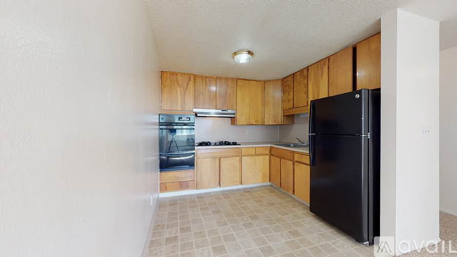 A kitchen with wooden cabinets and a black refrigerator.