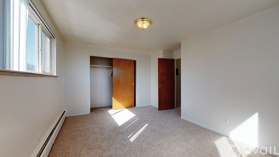 A room with a carpeted floor, a window, and two doors.