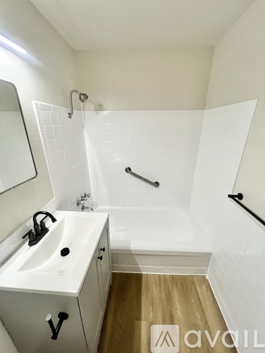 A white sink with a black faucet is in a white tiled bathroom.
