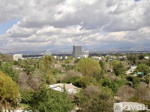 A cityscape with a large building in the center and trees in the foreground.