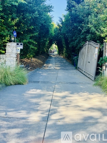 A sidewalk with a blue sign and a gate at the end.