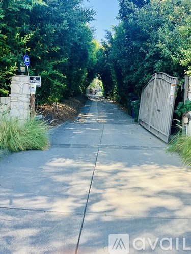 A sidewalk with a blue sign and a gate at the end.