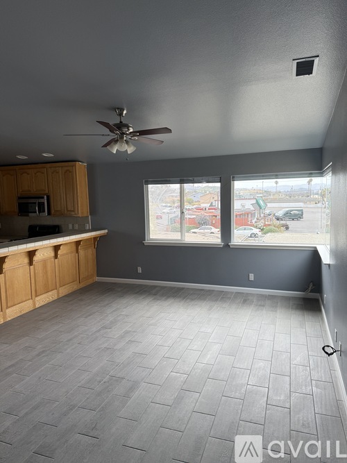 A room with a ceiling fan and a window overlooking a parking lot.