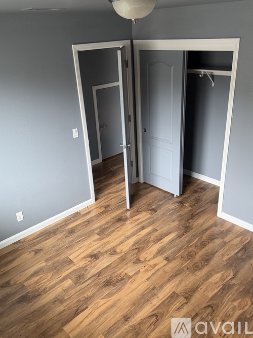 A room with wooden flooring and two doors.