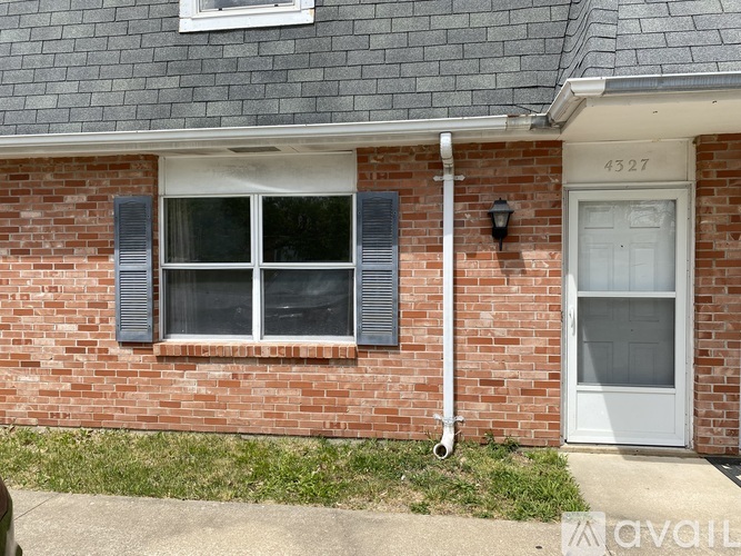 A brick house with a white door and window shutters.