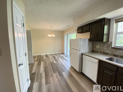 A kitchen with white appliances and wooden floors.
