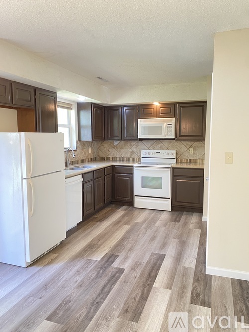 A kitchen with a white fridge and wooden cabinets.