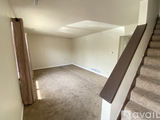 A room with a carpeted floor and a staircase leading to another room.