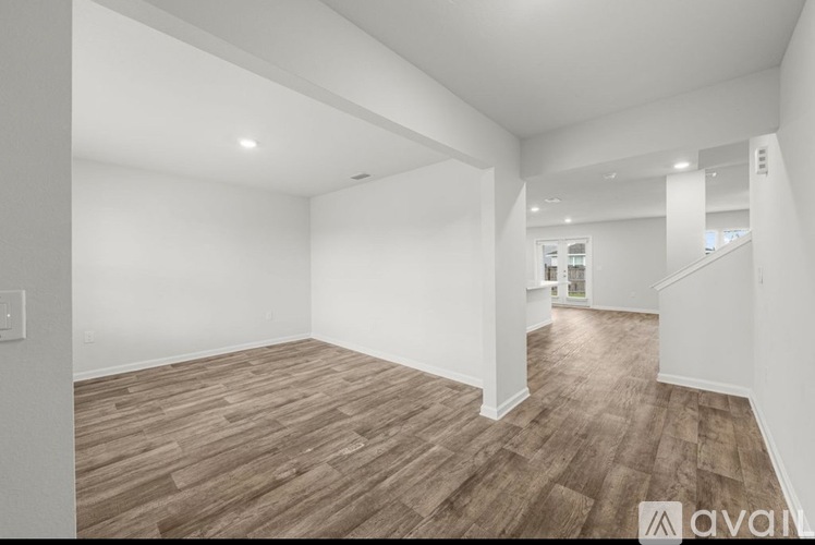 A spacious room with wooden flooring and white walls.