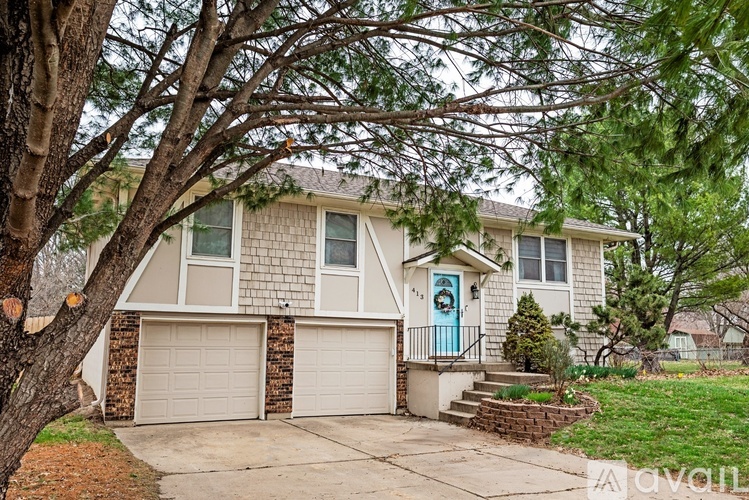A house with a blue door and a tree in front.