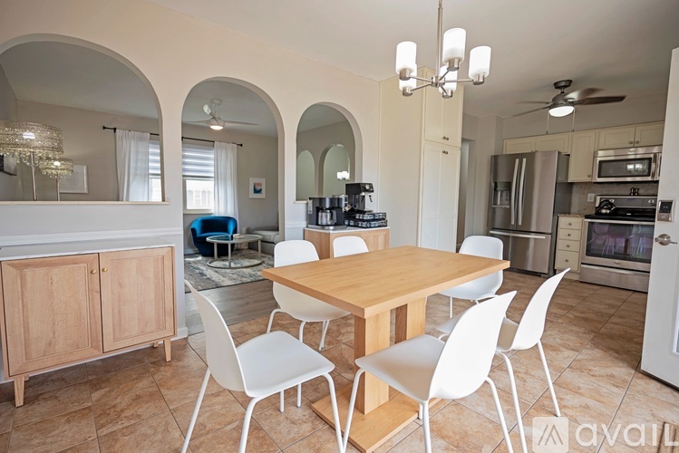 A dining room with a wooden table and white chairs.