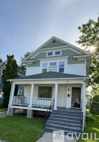 A two-story house with a front porch and stairs leading to the front door.