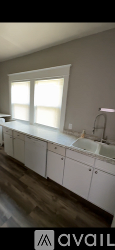 A bathroom with white cabinets and a window.