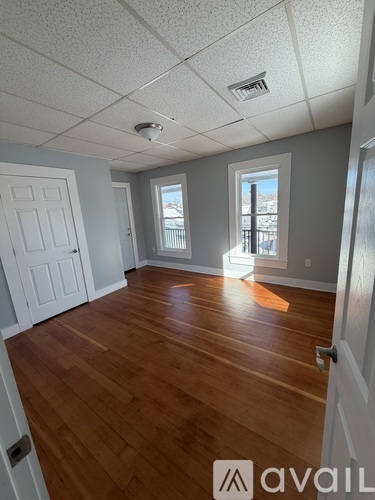 A room with wooden floors and a window overlooking a balcony.