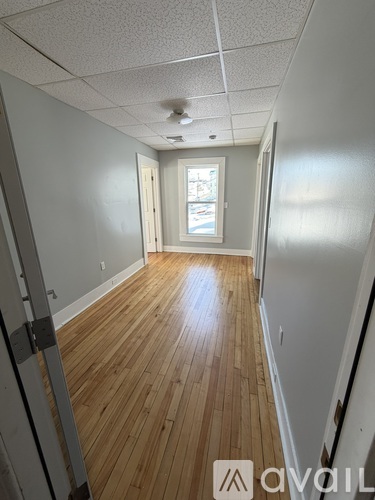 A long hallway with wood floors and white walls.
