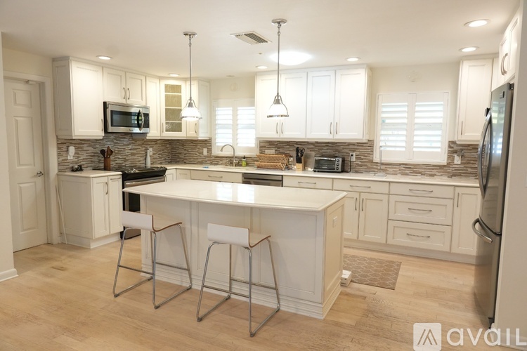 A kitchen with white cabinets and a large island.