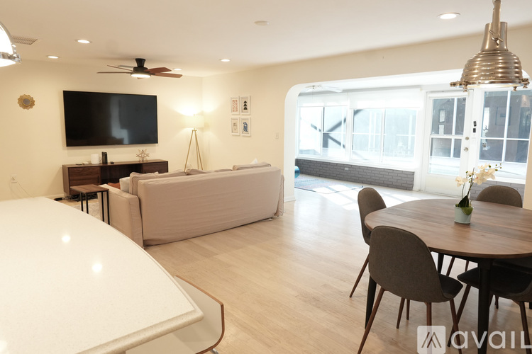 A living room with a white couch, a television, and a dining table with chairs.
