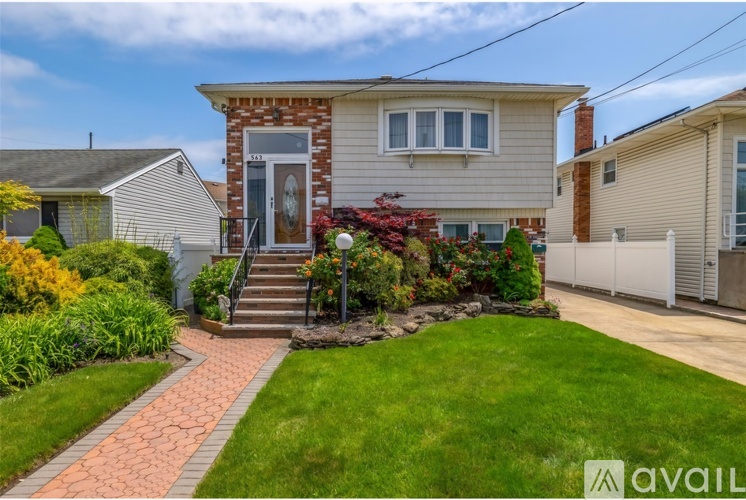 A house with a front yard and a brick pathway leading to the front door.