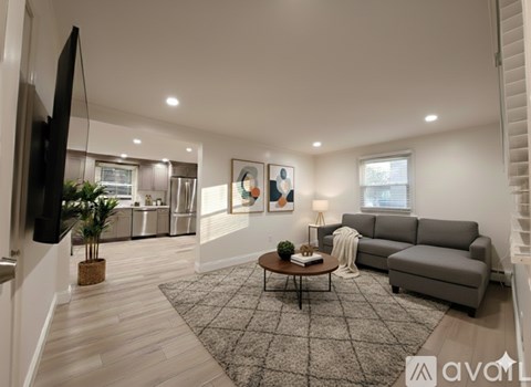 A living room with a grey couch, a coffee table, and a flat screen TV mounted on the wall.
